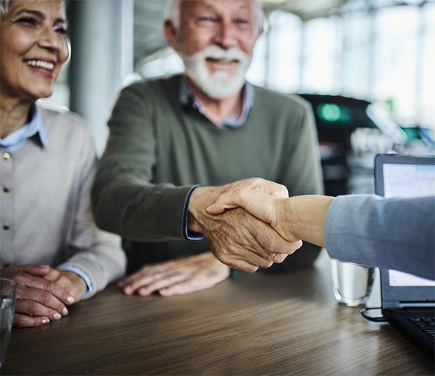 elderly man shaking hand with a person while seated at table